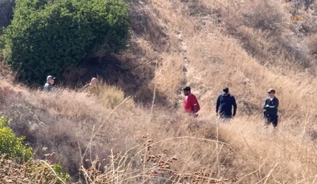 Jake Haro, in orange inmate attire, with San Bernardino County deputies during a search