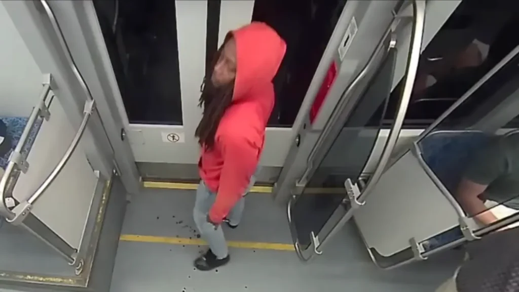Surveillance video still image of a man in a red hoodie on the light rail train
