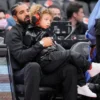 Drake sits with his son Adonis before the Toronto Raptors play the Philadelphia 76ers in their basketball game