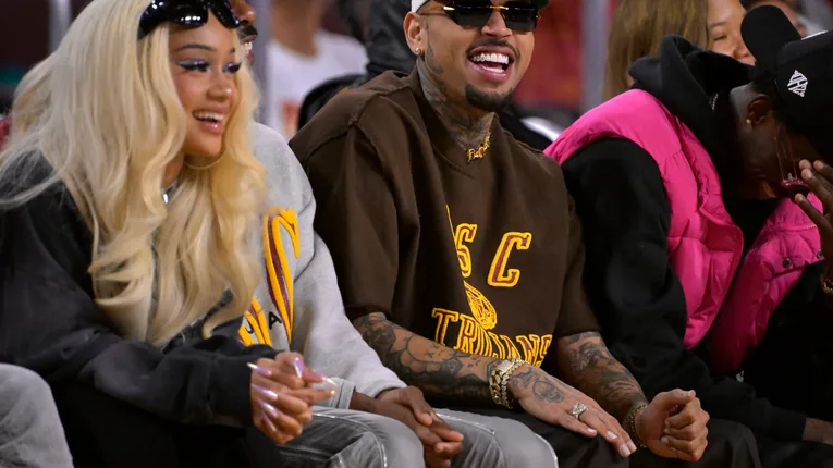 Rapper Saweetie fashion designer Tracey Mills and singer songwriter Chris Brown attend the game between the USC Trojans and the UCLA Bruins at Galen Center