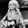 Country singer Dolly Parton performs onstage with an acoustic guitar in circa 1974.