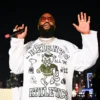 Under the night lights, Rick Ross rocks tinted aviator sunglasses and a diamond cuban link chain
